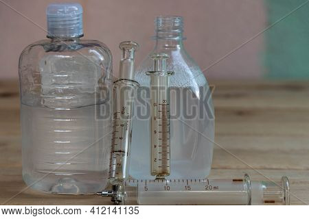 Bottles Of Alcohol Gel And Syringes On Wooden Background