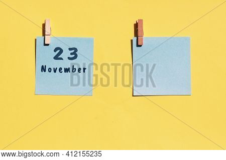 23 November. 23th Day Of The Month, Calendar Date. Two Blue Sheets For Writing On A Yellow Backgroun