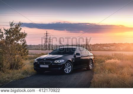 Kherson, Ukraine - June 2019. Black Bmw 5-series F10 On The Background Of A Beautiful Sunset.