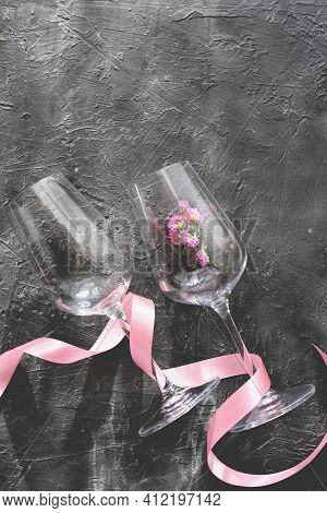 Wine Glasses With Pink Ribbon On Gray Background. Flower In A Wine Glass. Holiday Selebration Concep