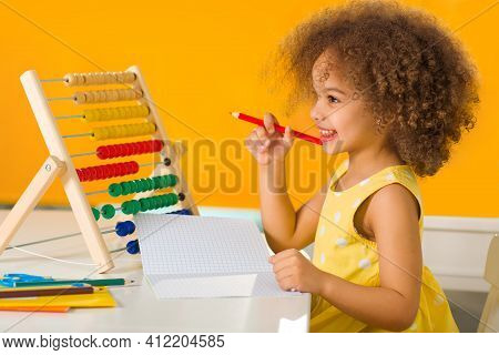A Black African-american Girl Is Ready For A Math And Arithmetic Lesson With An Abacus. A Buxom-hair