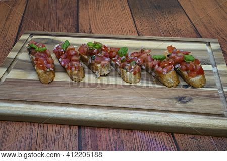 Ready Prepared Bruscetta Arranged On A Wooden Board.