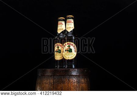 Bottle Of Birra Moretti Beer On Wooden Barrel With Dark Background. Illustrative Editorial Photo Buc