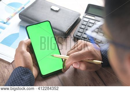 Rear View Of Man Hand Using Smart Phone On Office Desk