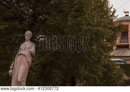 Sculpture Of A Woman Holding A Jug In The Park Of The New Palace, A Golden Deer On The Dome Of The W