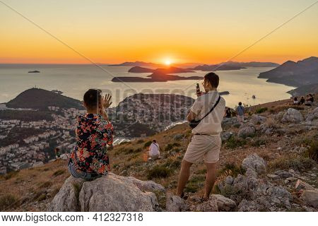 Tourists Take Photo Of Sunset Over Dubrovnik Old Town Adriatic Islands Coastline In Summer From Moun