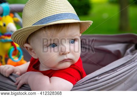 Cute Baby Boy Wearing A Hat Sitting Looking Out The Side Of His Stoller