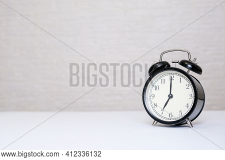 An Alarm Clock Showing 7 Oclock Standing On A White Table With Copy Space, Everyday Shedule And Morn