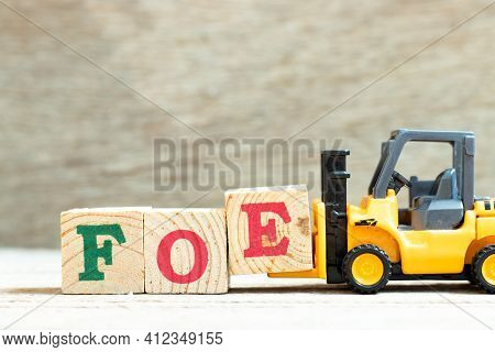 Toy Forklift Hold Letter Block E To Complete Word Foe On Wood Background