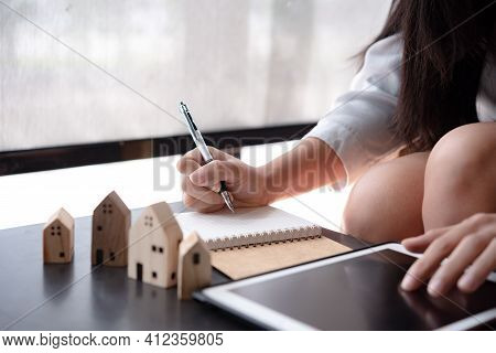 Wooden Toy House Medel With Woman Plan To Sign A Contract To Buy A House, Real Estate Concept.