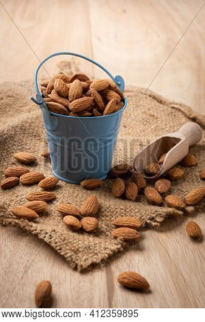 Almonds In Blue Bucket
 On Wooden Table. Almond Concept With Copyspace.