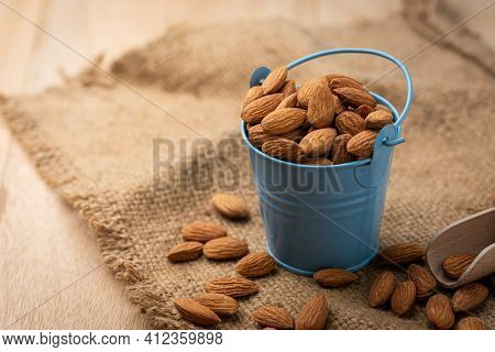 Almonds In Blue Bucket
 On Wooden Table. Almond Concept With Copyspace.