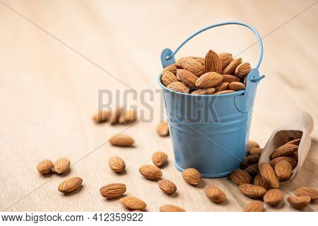 Almonds In Blue Bucket
 On Wooden Table. Almond Concept With Copyspace.