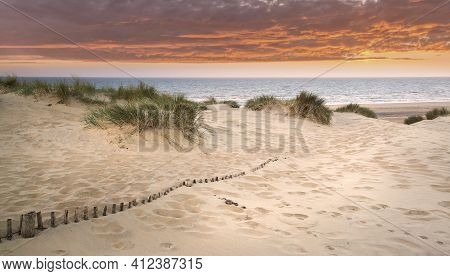 Landscape Of Grass In Sand Dunes At Snrise With Wooden Fences Under Sand Dunes