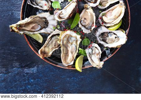 Oyster Season. Fresh Oysters Are Placed On A Round Plate With Ice And Lime. Seafood On Plate. Oyster