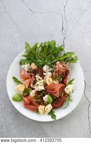 Salad Arugula, Parma Ham With Sun-dried Tomatoes, Mozzarella Slices, Croutons, Capers, Seasoned Oil 