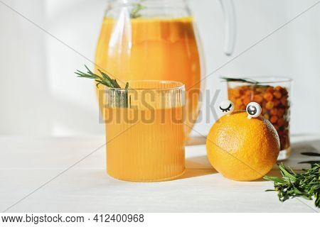 Funny Food Concept. Orange With Eyes And Orange And Sea Buckthorn Juice For Kids Menu. Rosemary Leav