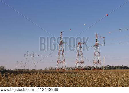 Colored Ball For Air Traffic Hangs From A High-voltage Cable. High Voltage Power Line Towers With Ba