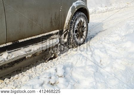 Road Snow Flies Up From A Vehicles Spinning Wheel. Cars Wheels Spin And Spew Up Pieces Of Snow It At
