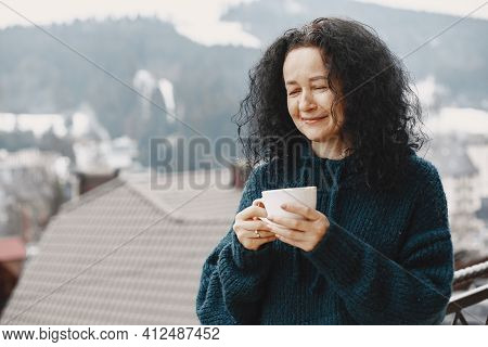Middle-aged Woman Drinking Coffee On Balcony In Winter Alone