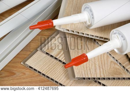 Set Of Items For Pvc Ceiling Indoor Works. Assembly Adhesive Bottles And Pvc Panels With Plastic Cor