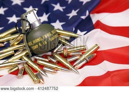 M67 Frag Grenade And Many Yellow Bullets And Cartridges On United States Flag. Concept Of Gun Traffi