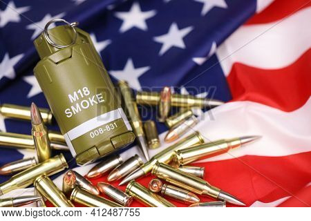 M18 Smoke Grenade And Many Yellow Bullets And Cartridges On United States Flag. Concept Of Gun Traff