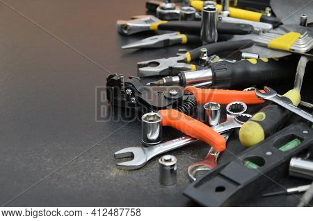 Handyman Tool Kit On Black Wooden Table. Many Wrenches And Screwdrivers, Pilers And Other Tools For 
