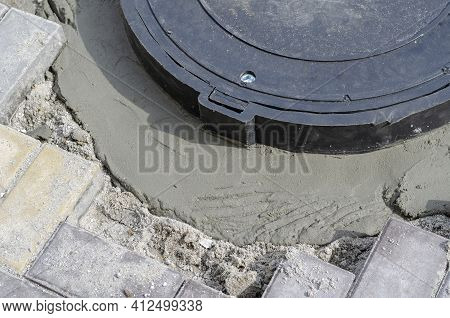 Installation Of A New Sewer Hatch. Fragment Of A Black Plastic Hatch In The Sidewalk With Uncured Ce