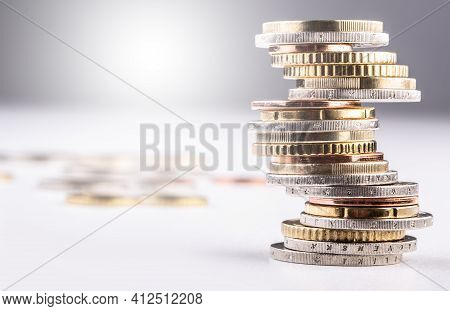 Pile Of Various Coins Stacked On An Imbalanced Column