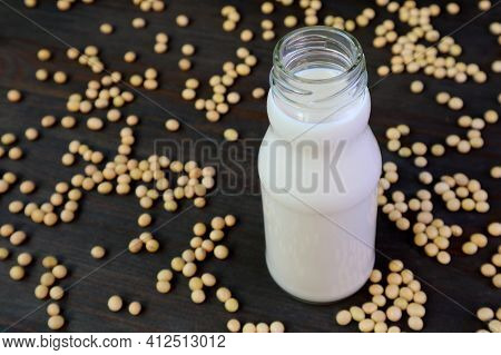 Bottle Of Soy Milk Isolated On Black Wooden Table With Scattered Soy Beans