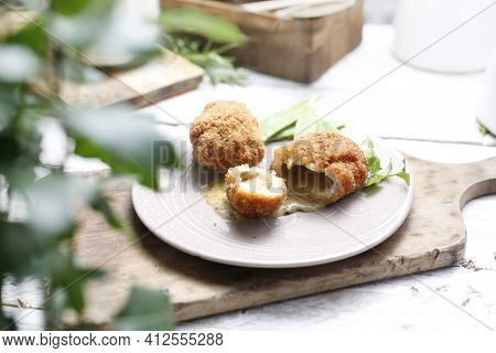 A Rustic Composition With Fried Chicken Kievs, Poultry Cutlets Whole And Halved, Served On A White P