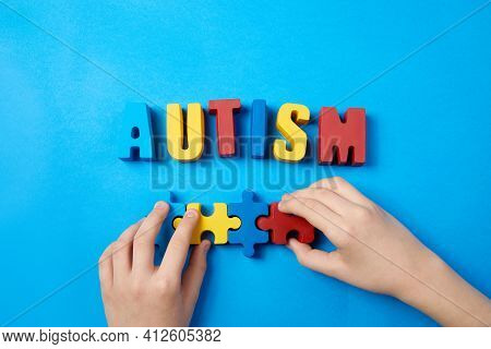 Autistic Kid Hands Holding Puzzle Jigsaw And Word Autism, Mental Health Concept. Autism Spectrum, Di