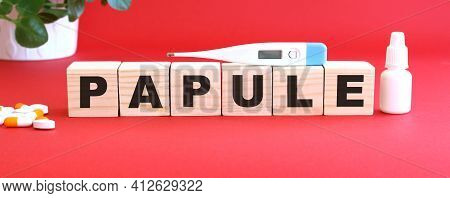 The Word Papule Is Made Of Wooden Cubes On A Red Background With Medical Drugs.