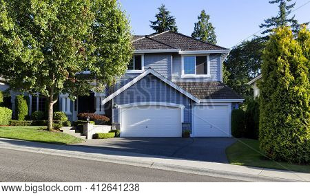 Curb View Of A Modern Home With Cedar Shake Roof During Summer Morning