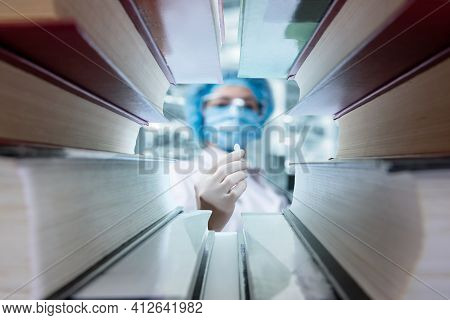 Doctor Shows A Pill For Treatment In Front Of Medical Textbooks.