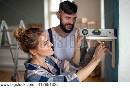 Mid Adults Couple With Leveler Indoors At Home, Relocation And Diy Concept.