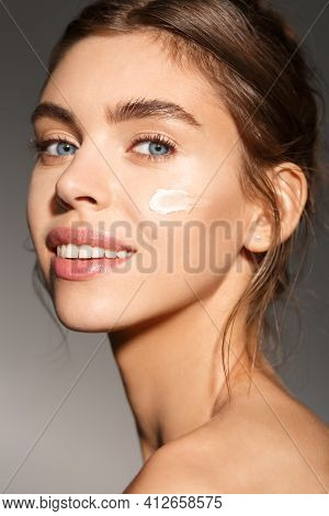 Face Skin Care. Woman Applying Cosmetic Cream On Clean Hydrated Skin Portrait. Beautiful Happy Smili