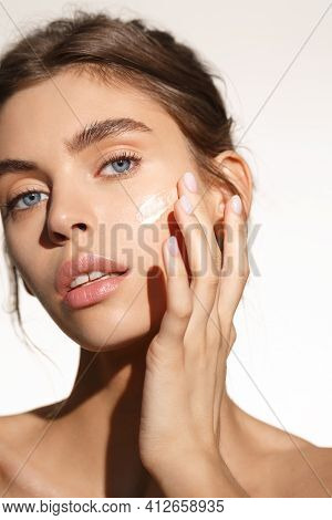 Face Skin Care. Woman Applying Cosmetic Cream On Clean Hydrated Skin Portrait. Beautiful Happy Smili