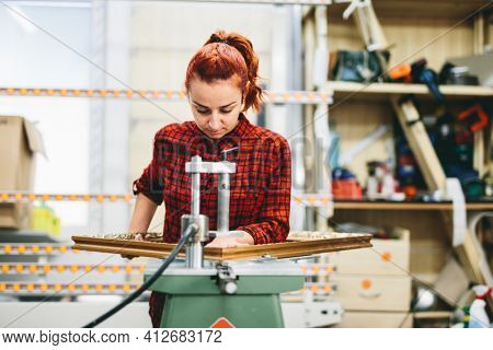 Woman worker sticking together a wooden frame with glue. Industry, manual work