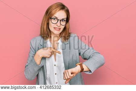 Young caucasian woman wearing business style and glasses in hurry pointing to watch time, impatience, upset and angry for deadline delay 
