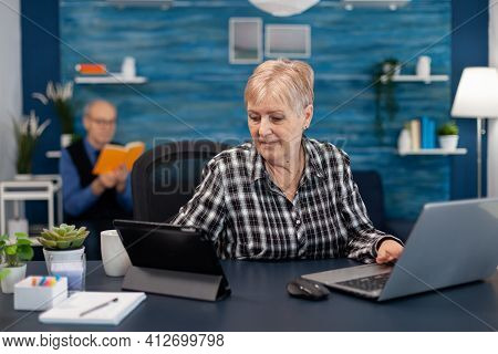 Senior Business Owner Working From Home Office Using Portable Computer. Elderly Woman In Home Living