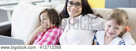 Smiling Woman Is Sitting On Sofa With Girls.