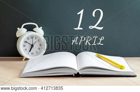 April 12. 12th Day Of The Month, Calendar Date.white Alarm Clock, An Open Notebook With Blank Pages,