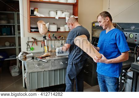 Two Prosthetist Man Workers Making Prosthetic Leg While Working In Laboratory.