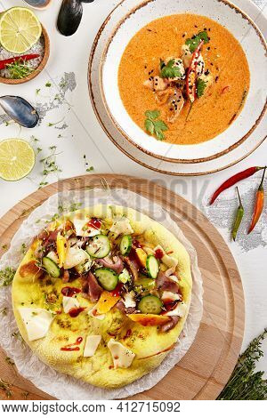 Tom yum soup and focaccia bread. Top view of food set with ingredients on white table