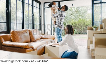 Happy African American Young Family Bought New House. Mom, Dad, And Child Happy Hold Cardboard Boxes