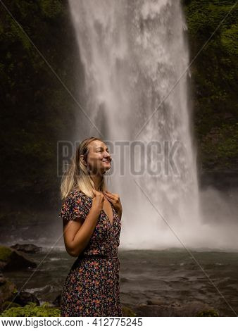 Happy Woman Smiling And Enjoying Waterfall Landscape. Nature And Environment Concept. Travel Lifesty