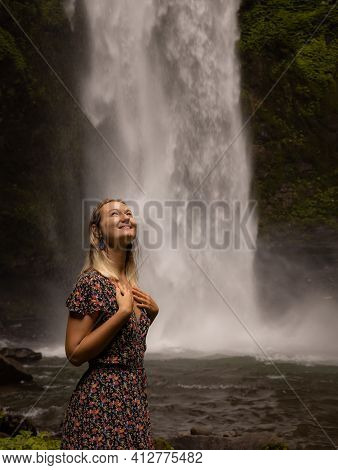 Happy Woman Smiling And Enjoying Waterfall Landscape. Nature And Environment Concept. Travel Lifesty