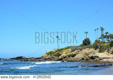 Rocky Coastline in Laguna Beach, California as a flock of pelicans soars over Recreation Point.